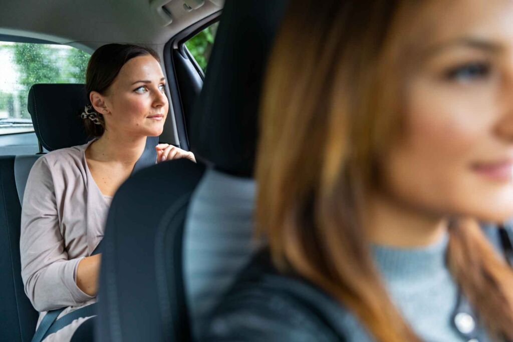 A woman using a rideshare service while another woman is driving