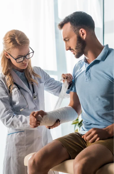 A doctor gently wraps a bandage around a patient's injured arm in a well-lit medical setting.